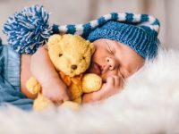 Baby newborn portrait, boy kid newborn sleeping in blue hat with teddy bear